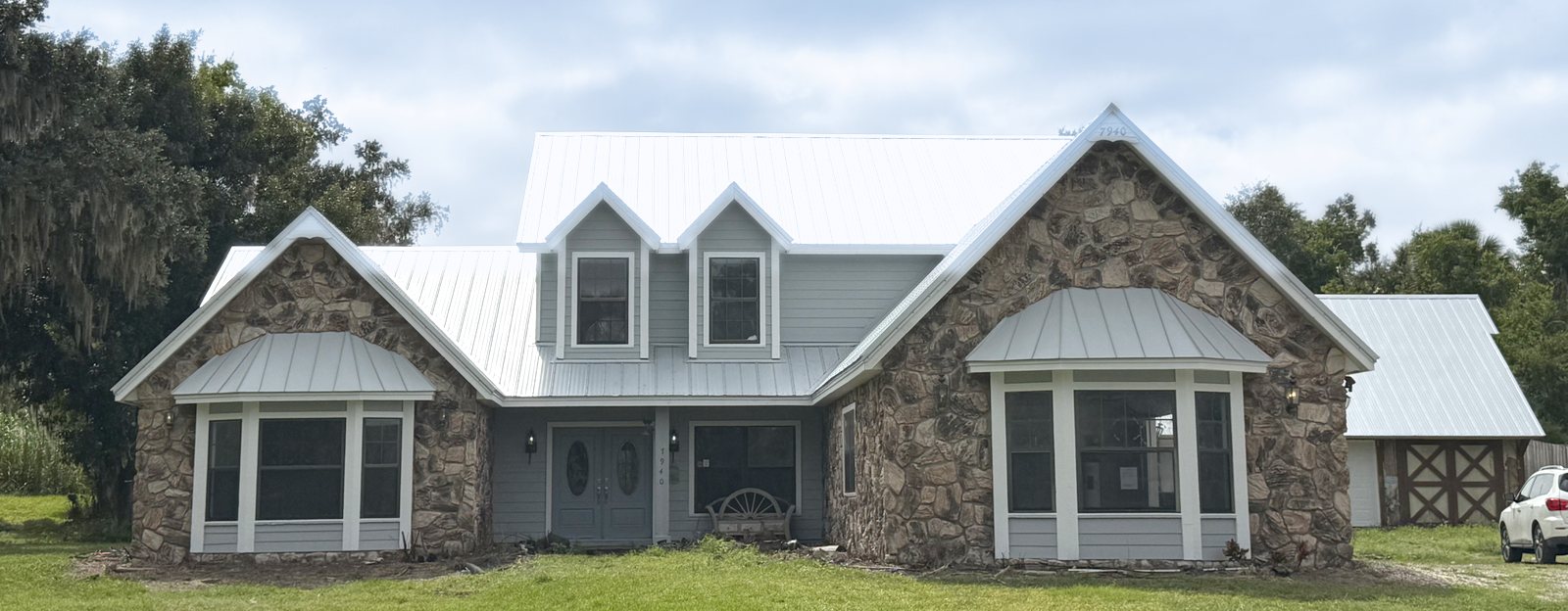 A finished Florida Doug Services project: a stone and siding home with a white metal roof in the Manatee County area.